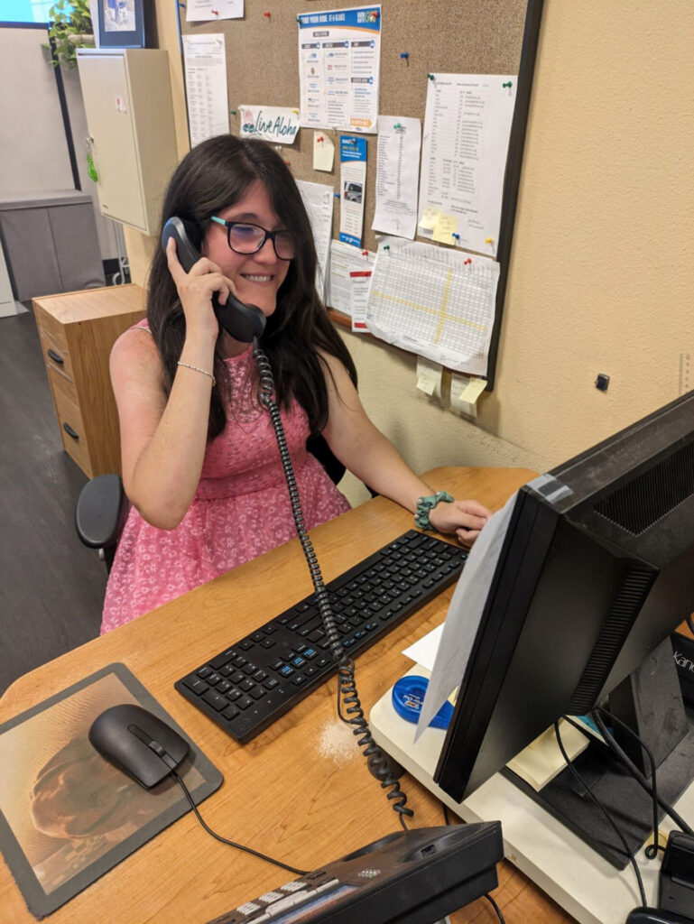 Makayla at UCP/Ride-On offices, smiling while answering a phone call