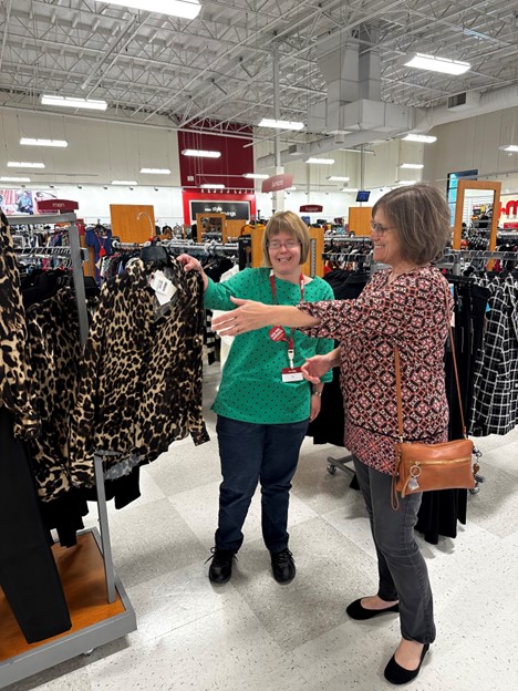 Amy smiling at her job while showcasing a jacket to a customer