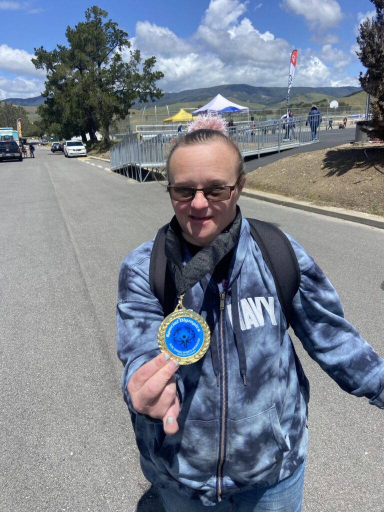 Jenny showcasing her medal while walking back to her car after her event