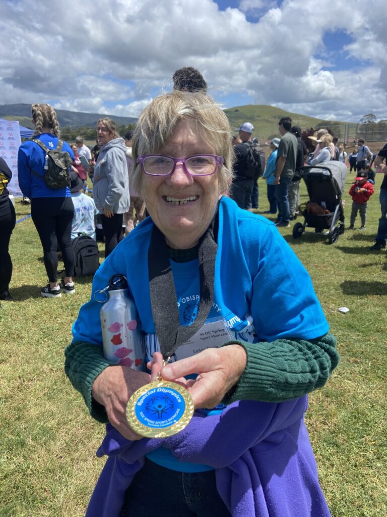 Leann smiling and proudly holding her medal and a water bottle after her event
