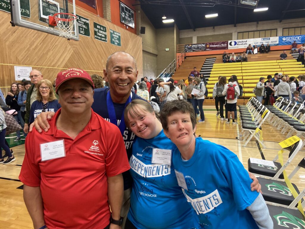 Athletes smiling for the camera in a gym after a game